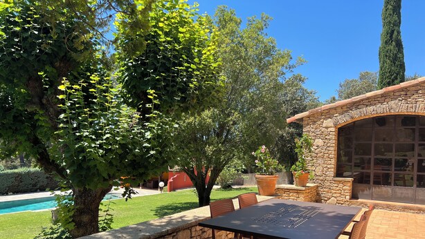 Un patio al aire libre con paredes de piedra, una piscina y un edificio de piedra con ventanas amplias.