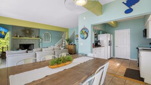 A cozy living room with a fireplace, a dining area with a wooden table, and a kitchen with a refrigerator and cabinets.