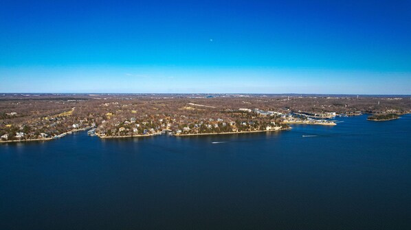 Vista aérea de una comunidad junto al lago, con edificios residenciales, barcos y una pequeña isla.