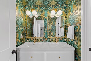 A bathroom with a large mirror, two sinks, and a wall with a floral wallpaper pattern. - Gather the Fam! Close to everything, Home Theater, 2 Kitchens, 2 Living Rooms! (Wisconsin Dells)