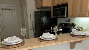 A kitchen with wooden cabinets, a black refrigerator, a stove, and a bar area with stools. - Pacific University Stay,  very close to the University and downtown Forest Grove (Forest Grove)