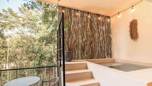 A modern balcony with a glass-top table and chairs, a staircase, and a decorative wall with vertical elements. - Balam Bohemian Paradise Beach Club + Private Pool (Tulum)
