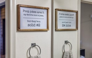 Två inramade skyltar på en vägg, var och en med ett humoristiskt budskap om skämt som handlar om avföring.