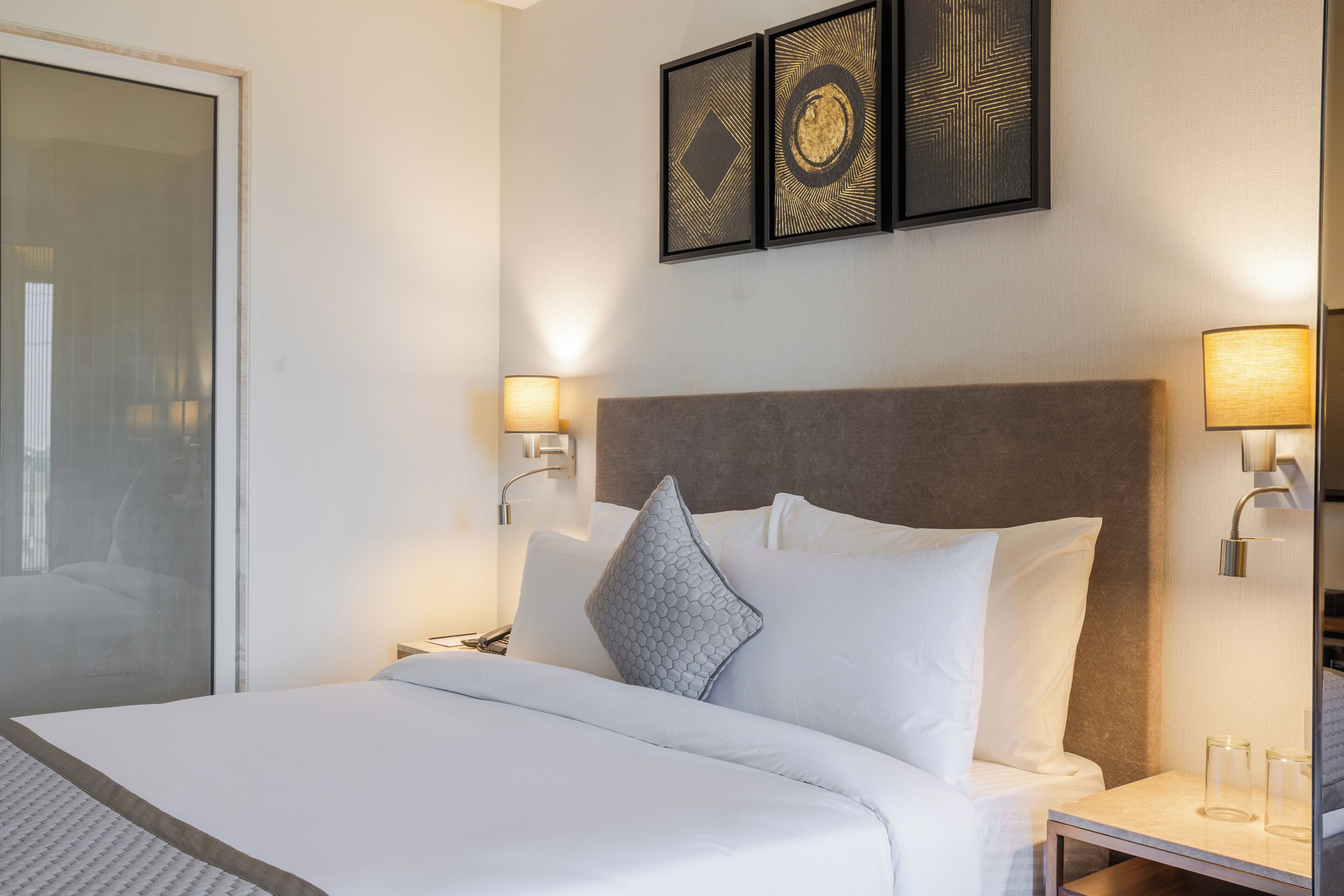 A hotel room with a large bed, two bedside lamps, a nightstand, and a wall-mounted picture frame.