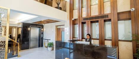 Un vestíbulo de hotel con una recepción, una escalera y una planta grande en maceta.