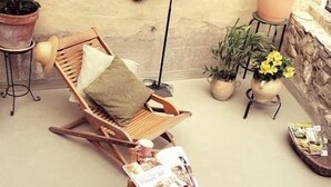 A wooden rocking chair with a cushion, a magazine on a small table, and potted plants. - The Marquis refuge: Pleasant T3 with terrace (Marsanne)