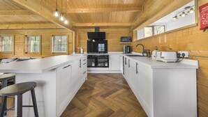 Een moderne keuken met witte kasten, een centraal eiland en een houten plafond.