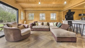 Een gezellige woonkamer met een hoekbank, een ronde fauteuil en een bar met barkrukken.