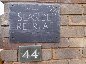 A sign for 'Seaside Retreat' with a number '44' below it, mounted on a brick wall. - Seaside Retreat (Skegness)