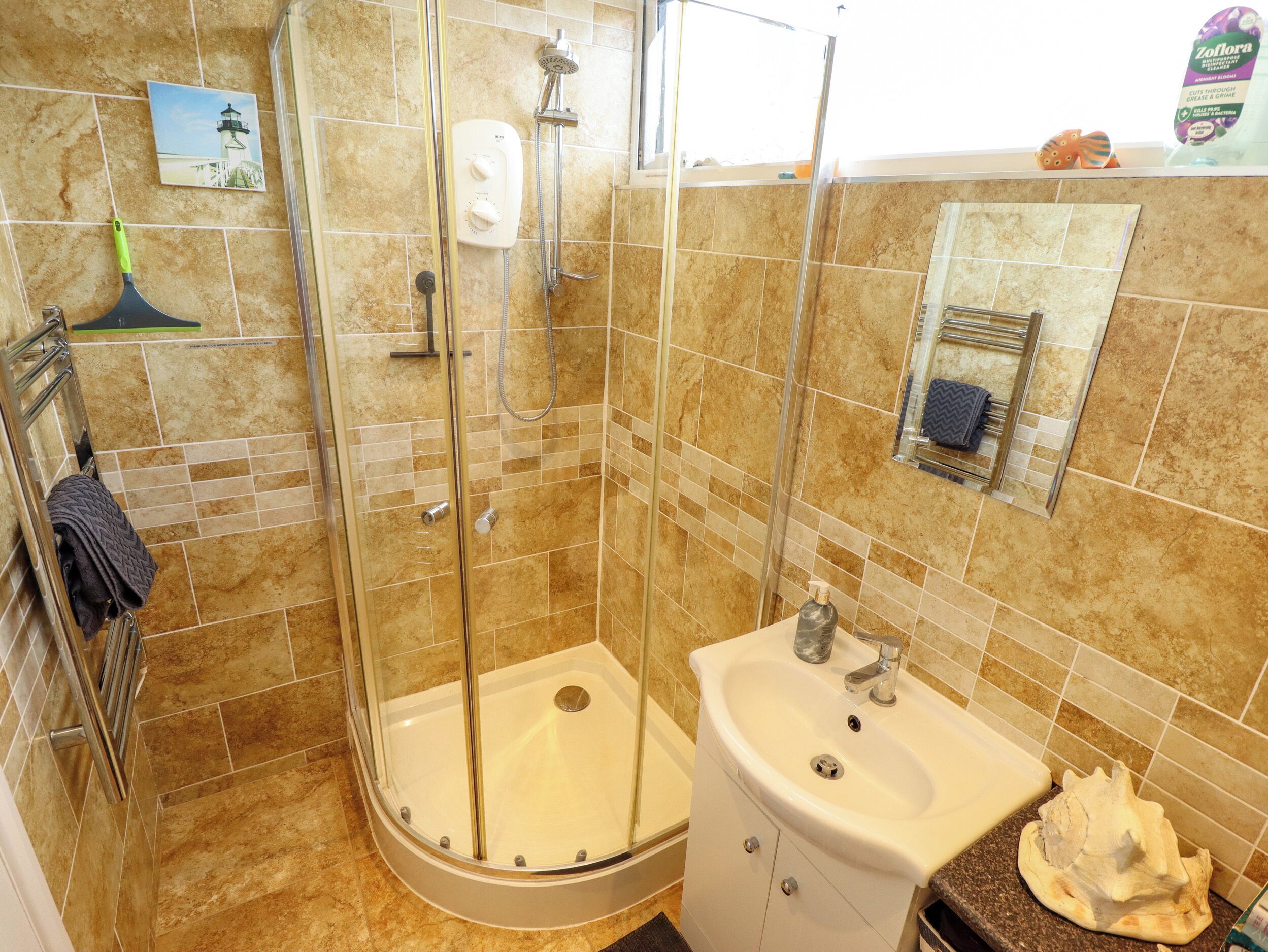 A bathroom with a glass-enclosed shower, a sink, and a mirror.