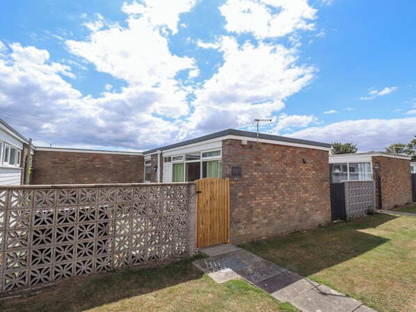A residential property with a brick exterior, a gated entrance, and a clear sky. - Seaside Retreat (Skegness)