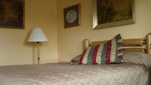A bed with a quilted cover, a bedside lamp, and two pillows. There are framed pictures on the wall. - Rainbow Lodge (Lakeport)