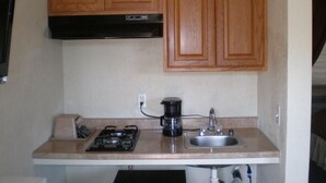 A compact kitchen with wooden cabinets, a gas stove, a coffee maker, and a sink. - Rainbow Lodge (Lakeport)