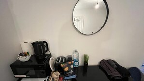A neatly organized desk with a black coffee maker, a toaster, a kettle, a water bottle, a small plant, and a rolled-up towel. - Contractors - Families - Couples - 3x Bedrooms + Sofa Bed - Sleeps 8 M1 J26&25 (Ilkeston)