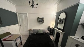 A compact living space with a black carpet, a white sofa, a small table, a fireplace, and a mirror on the wall. - Contractors - Families - Couples - 3x Bedrooms + Sofa Bed - Sleeps 8 M1 J26&25 (Ilkeston)