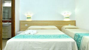 A hotel room with two beds, a wooden headboard, a bathroom with a sink and mirror, and wall-mounted lights. - Calajunco1985 Sardinia Travel Experience (Loiri Porto San Paolo)