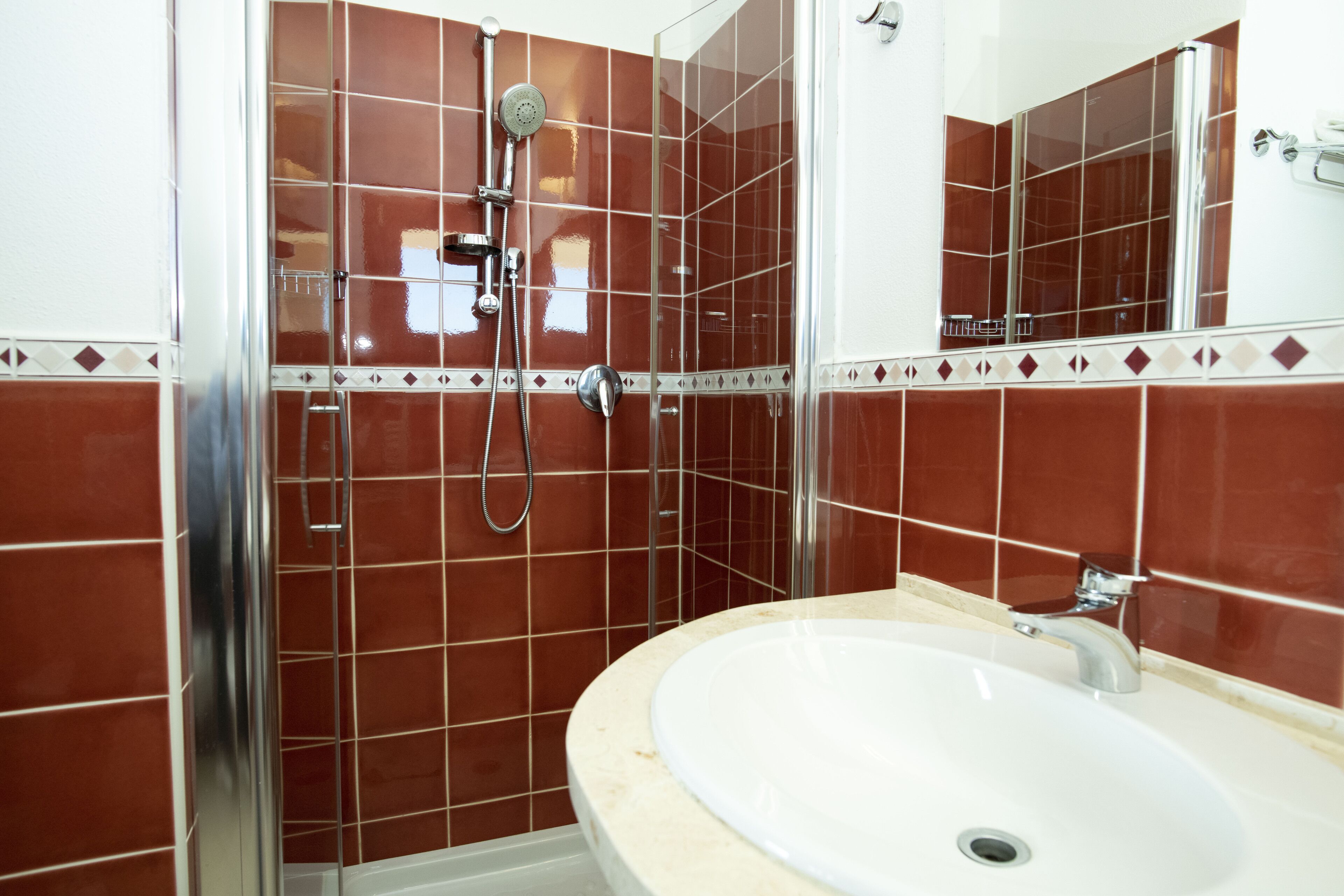 A bathroom with a shower, a sink, and a mirror.