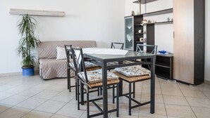 Un comedor con una mesa y sillas, un sofá, un armario y una planta en maceta.