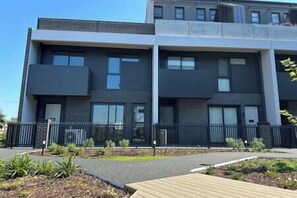 Un edificio moderno de dos pisos con techo plano, ventanas amplias y un sendero pavimentado en la parte delantera.