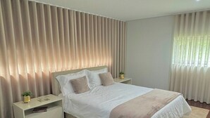 Een moderne slaapkamer met een groot bed, een nachtkastje, een wandlamp en een nachttafel.