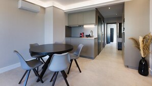 A modern kitchen with a central island, grey cabinetry, and a dining area with a round table and four chairs. - Antibes Calm: Your Coastal Haven (Antibes)