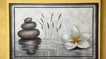 A framed artwork with stacked stones, grasses, and a white flower.