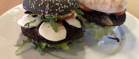 A burger with a sesame seed bun and a side of flatbread on a white plate.