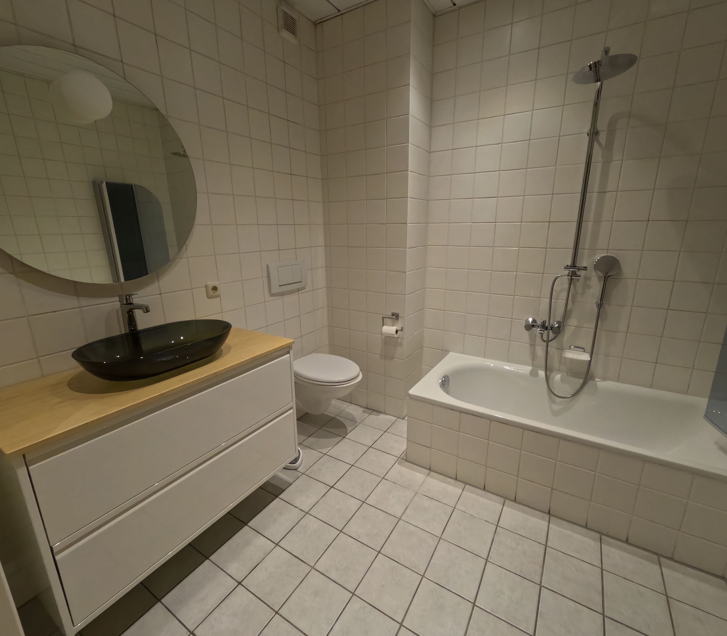 A bathroom with a bathtub, toilet, sink with a bowl, and a mirror.