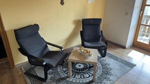 Two dark-colored chairs, a small wooden table with a decorative rug, and a yellow wall with a small light fixture. - Gasthof & Pension Zum Zacherwirt (Hengersberg)