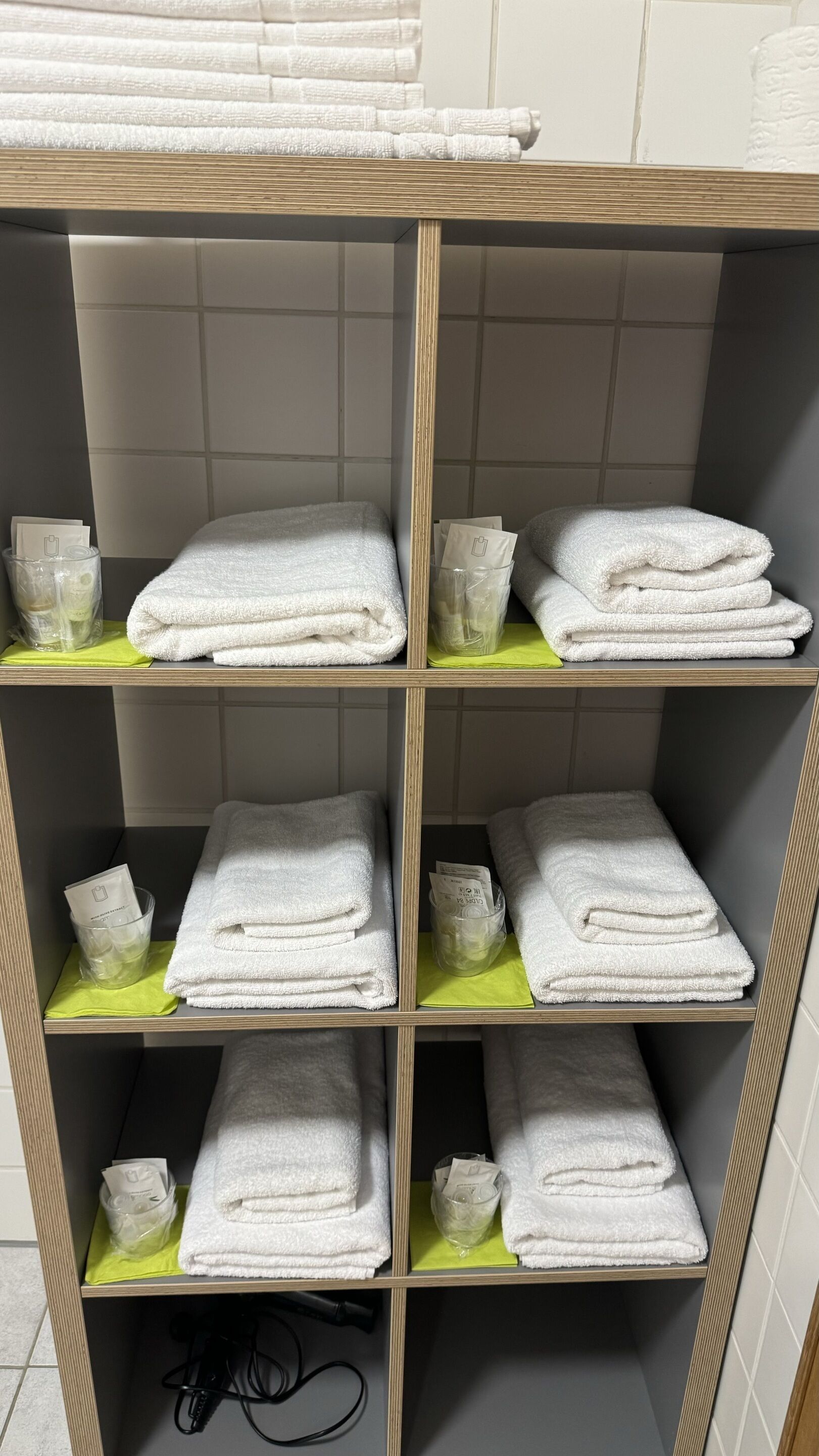 Un depósito con estanterías que exhiben toallas blancas dobladas con pulcritud y bolsas de plástico transparentes, presumiblemente con artículos de aseo.