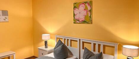 Een slaapkamer met twee bedden, een houten plafond en een schilderij aan de muur.