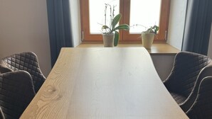 A dining table with two chairs, a window with curtains, and two potted plants on the windowsill. - Gasthof & Pension Zum Zacherwirt (Hengersberg)