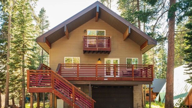 Une cabane en rondins à deux étages, dotée d’un balcon et d’un escalier.