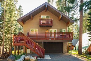 Une cabane en rondins à deux étages, dotée d’un balcon et d’un escalier.