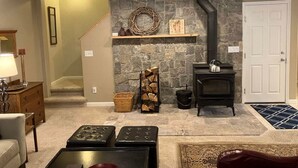 Un salon chaleureux avec un mur en pierre, une cheminée et un ventilateur de plafond.