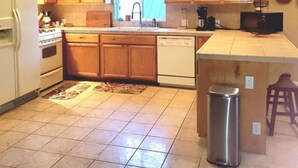 Une cuisine avec des meubles de rangement en bois, une cuisinière, un lave-vaisselle et une poubelle.