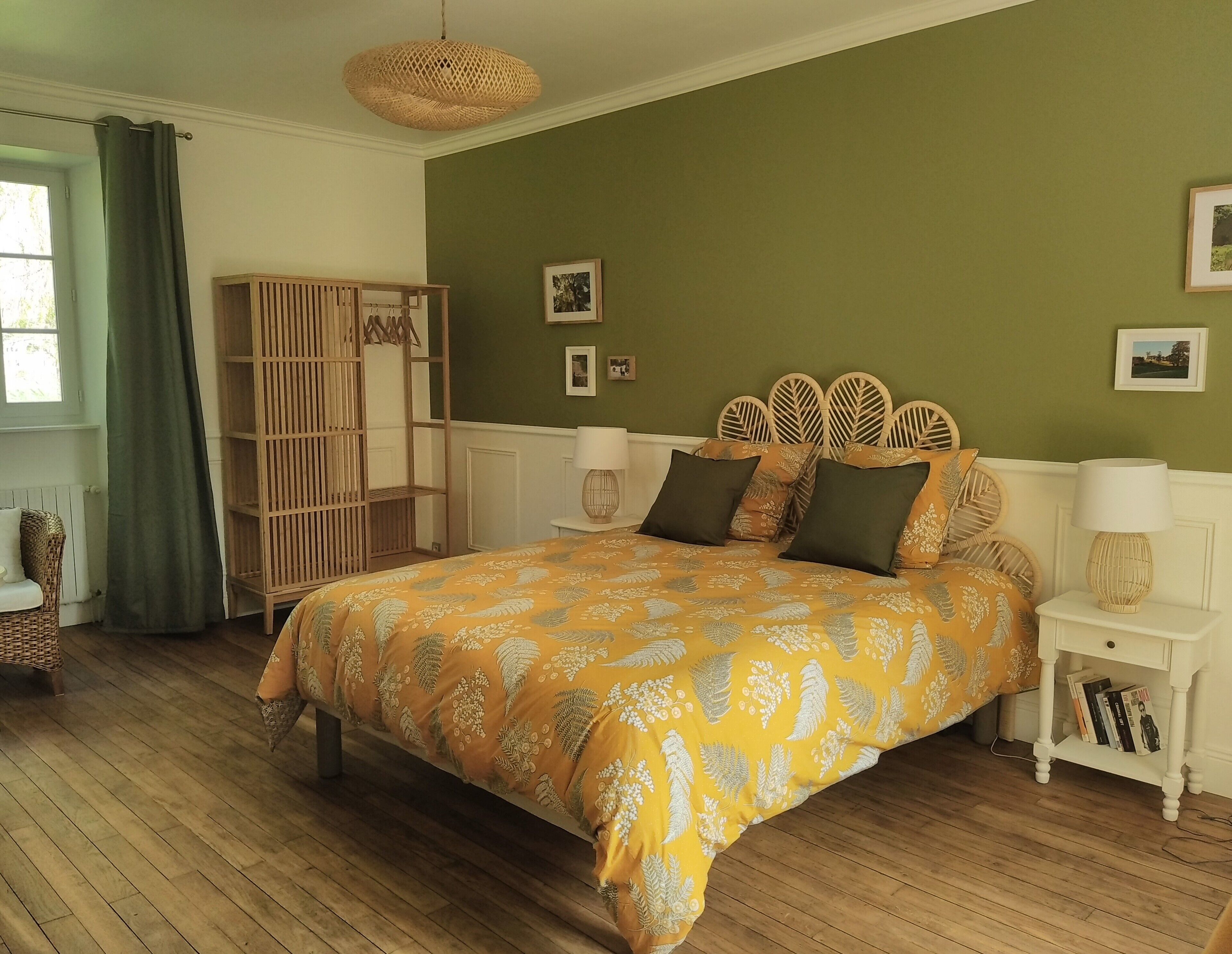 A bedroom with a bed, wooden wardrobe, bedside tables, and a hanging light fixture.