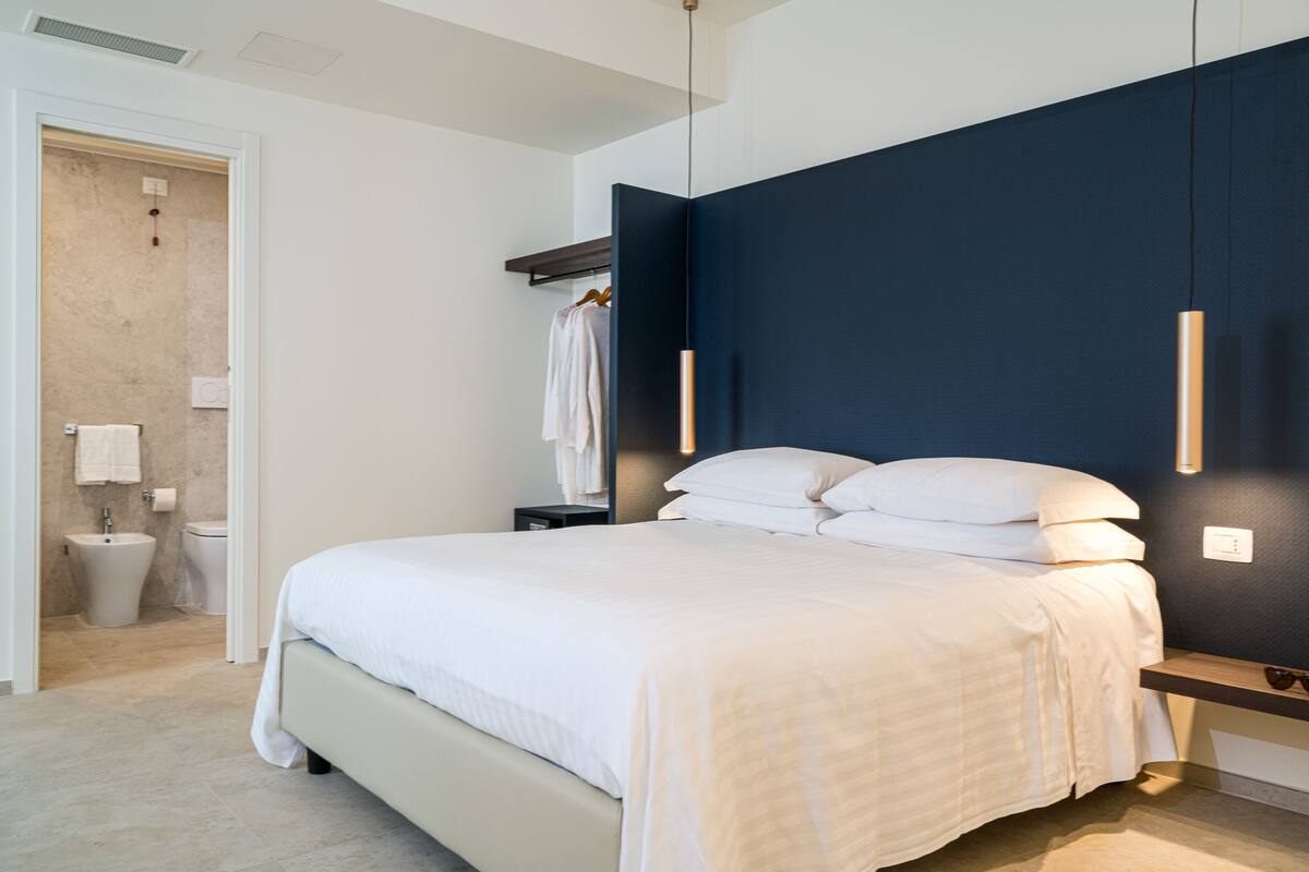 Een moderne slaapkamer met een groot bed, een nachtkastje en een bijzettafeltje.