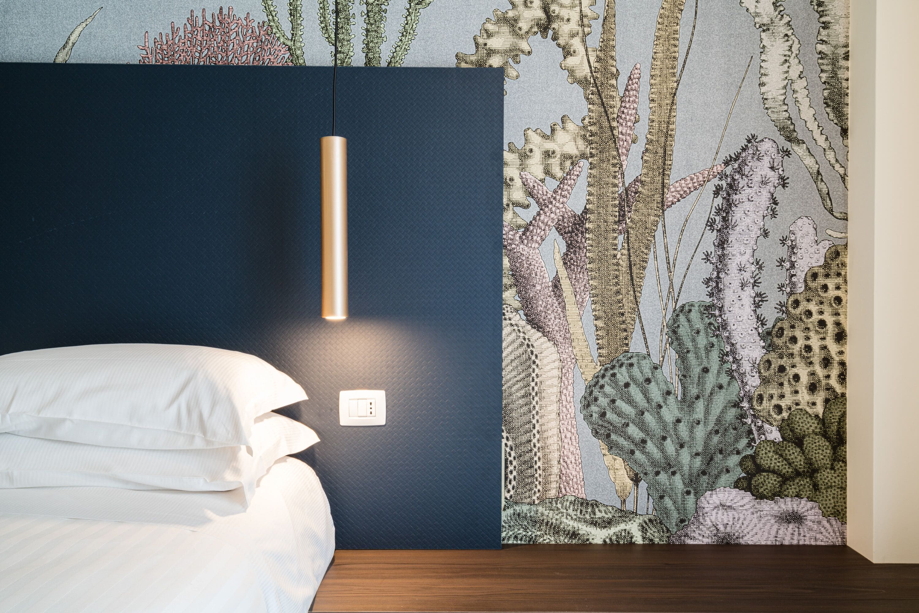 Una camera da letto con un letto, una lampada a parete e carta da parati a tema cactus.