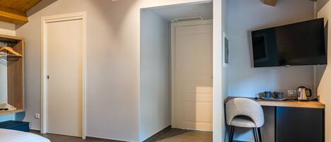 Una habitación de hotel con dos camas, un escritorio con silla, televisión y una kitchenette.