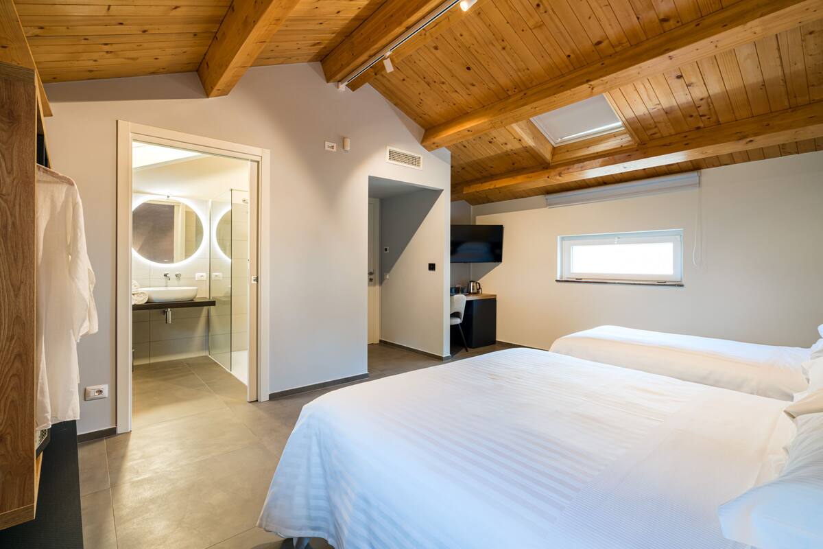 Een slaapkamer met een groot bed, een bureau, een televisie en een dakraam.