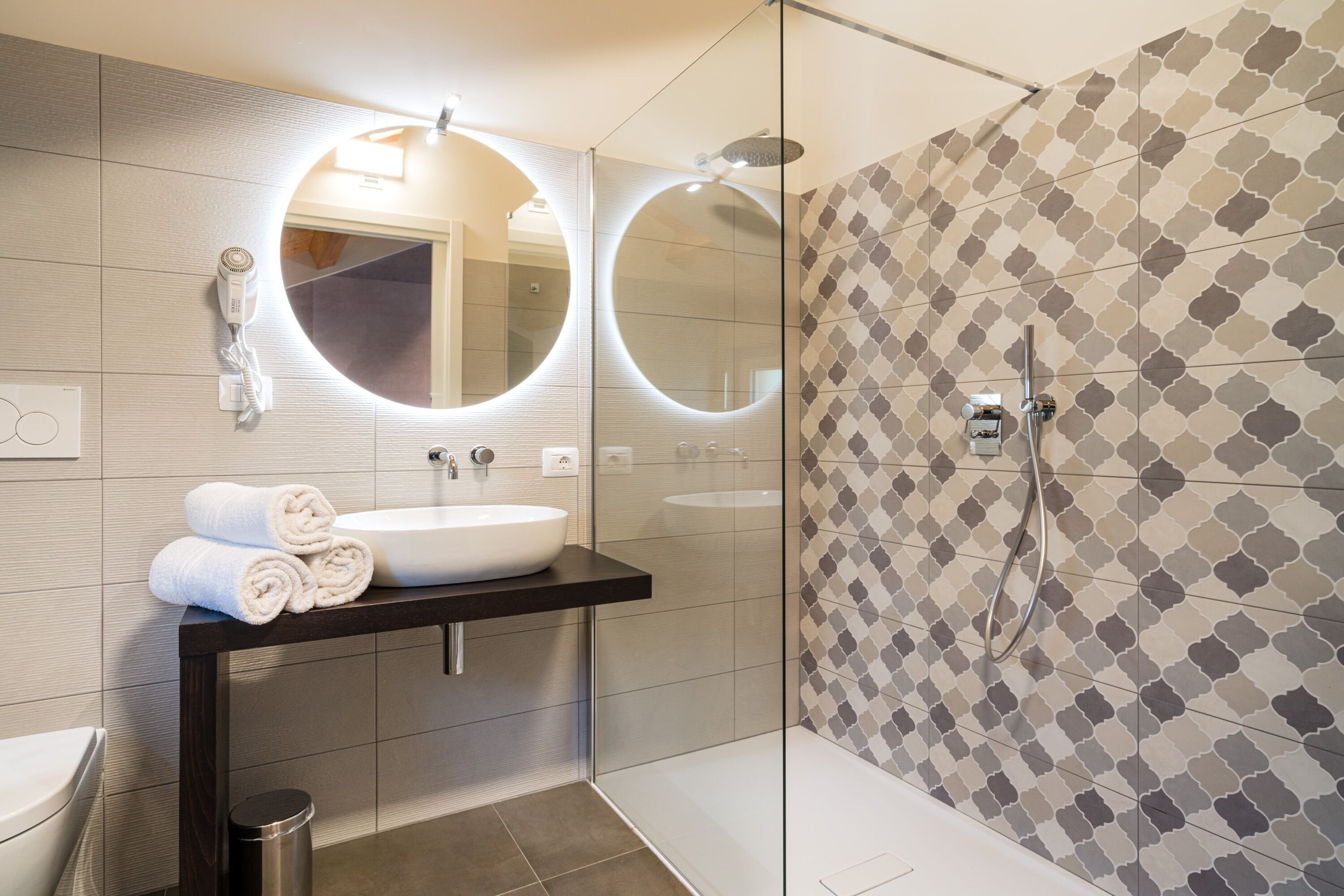 A modern bathroom with a round mirror, a sink, and a shower.