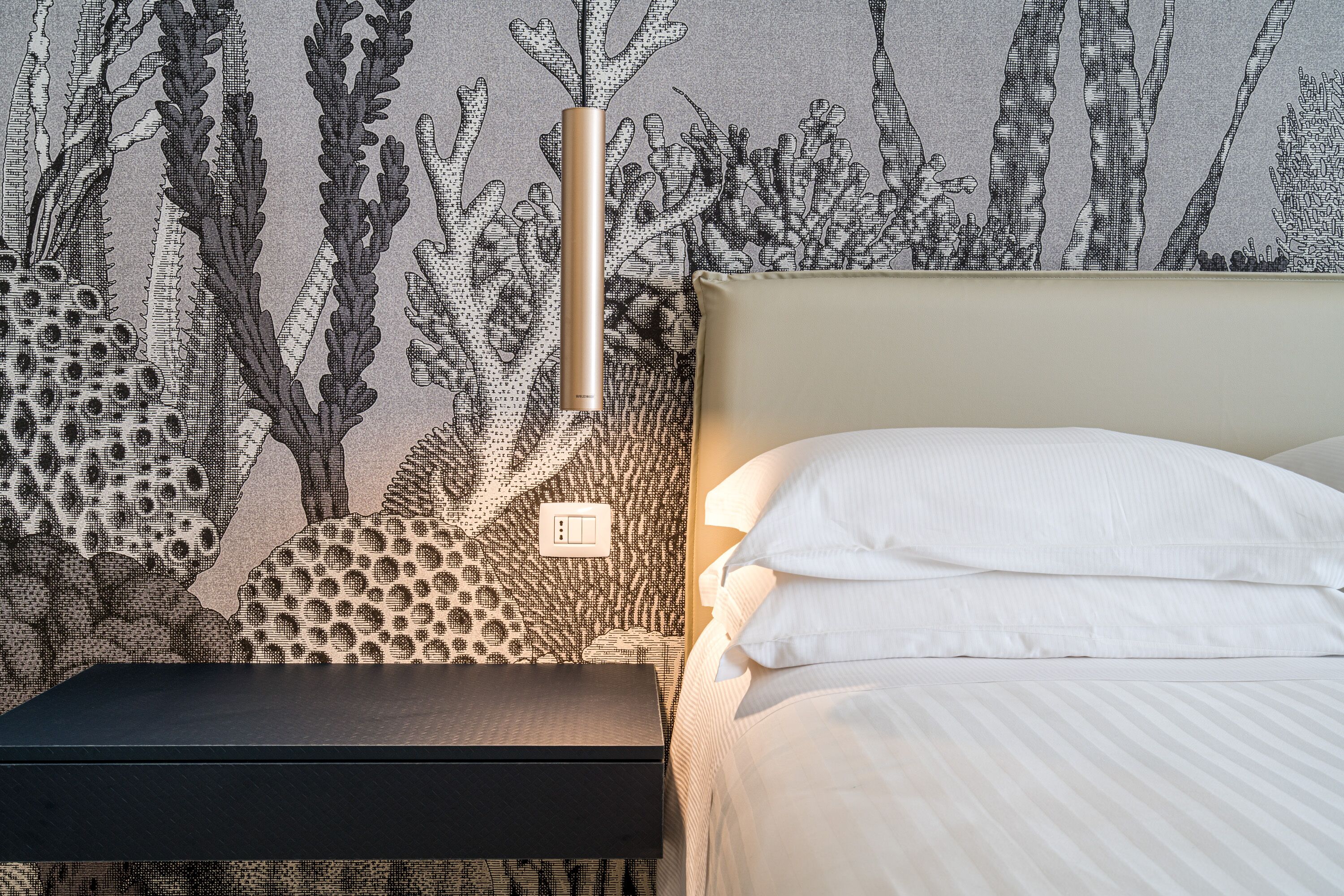 Una camera da letto con un letto, un comodino e una parete decorata con un motivo a barriera corallina.