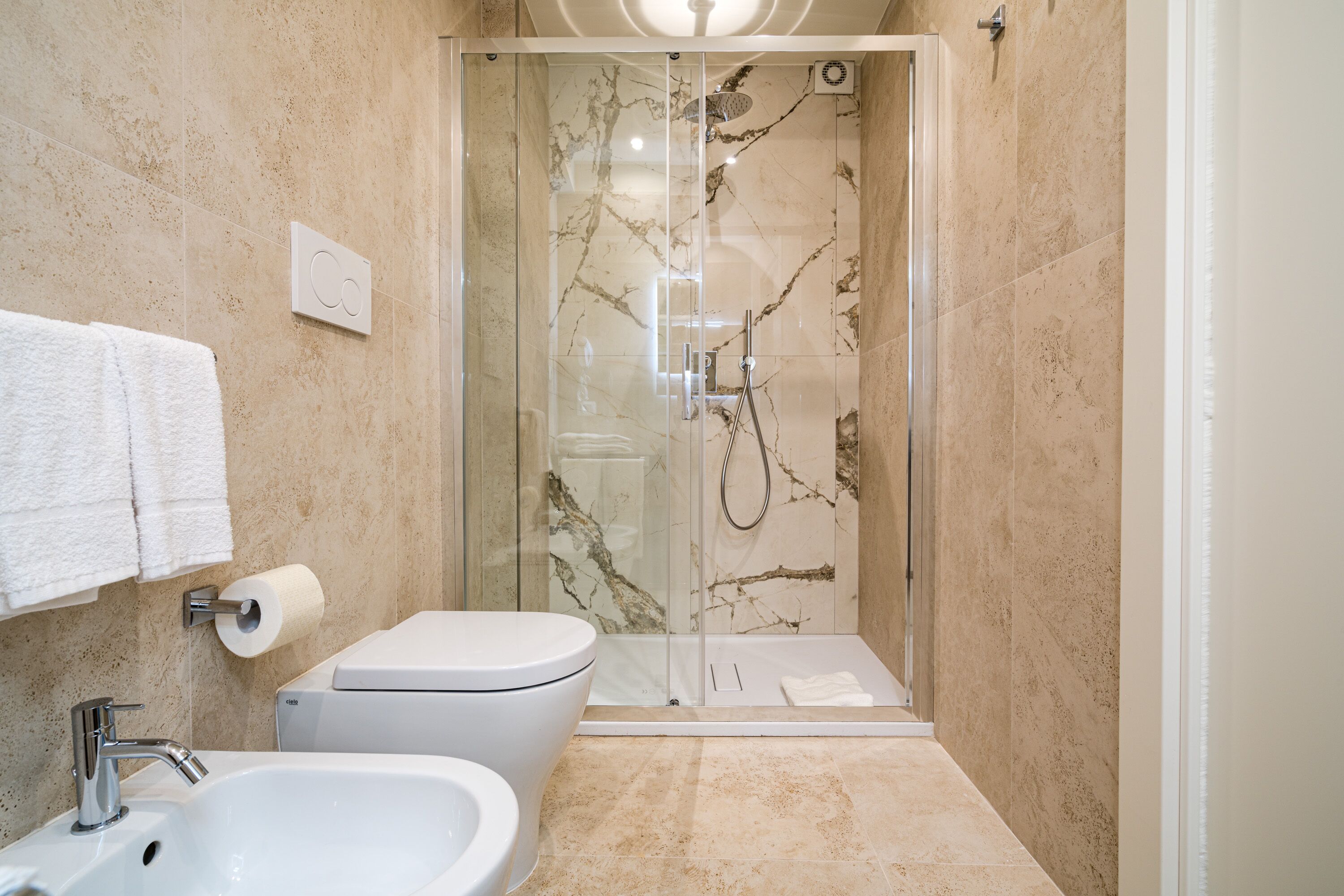 A modern bathroom with a glass-enclosed shower, a sink, and a toilet.