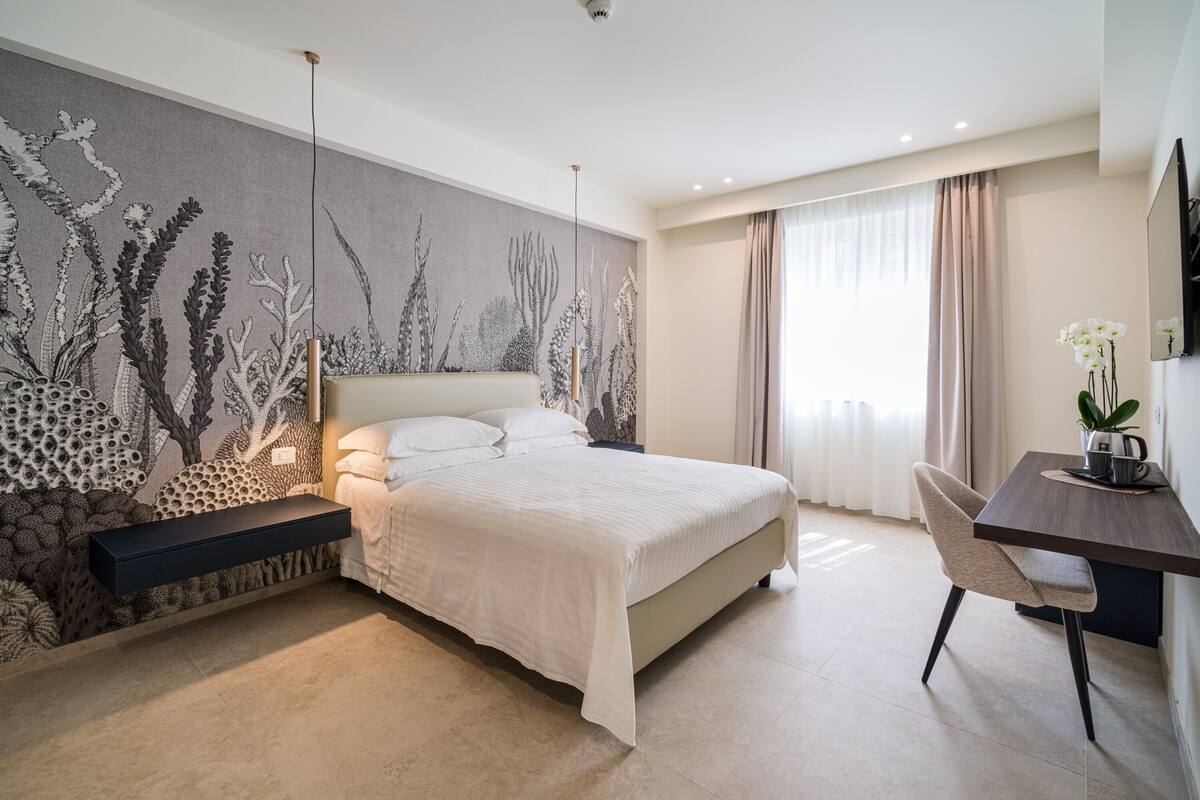 Een moderne hotelkamer met een groot bed, een bureau en een muurschildering.