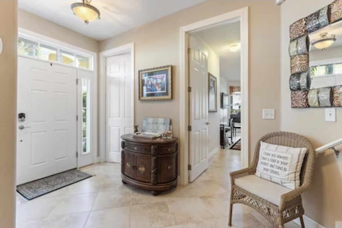 A hallway with a door, a cabinet, a wicker chair, and a wall-mounted artwork.