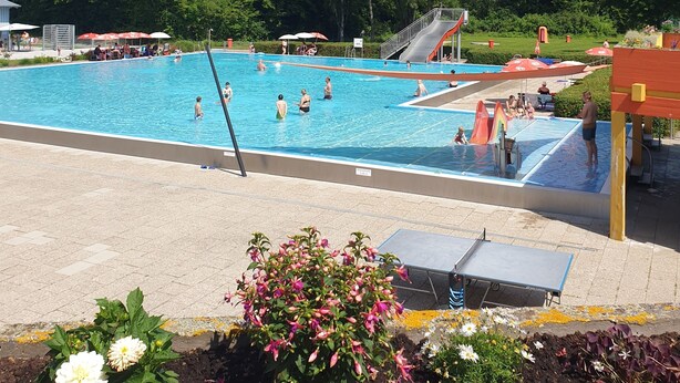 A swimming pool with a slide, surrounded by greenery and a clear sky. - Appartement mit gr. Garten u. 2 Bäder (Vilshofen an der Donau)