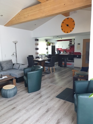 Una sala de estar moderna con un sofá, sillas y una zona de comedor con mesa y sillas.