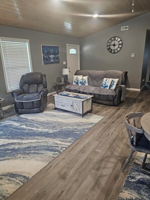 A living room with a leather armchair, a sofa, a coffee table, and a rug.