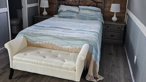 Een slaapkamer met een bed, twee nachtkastjes, een plafondventilator, een raam en een houten wandpaneel.